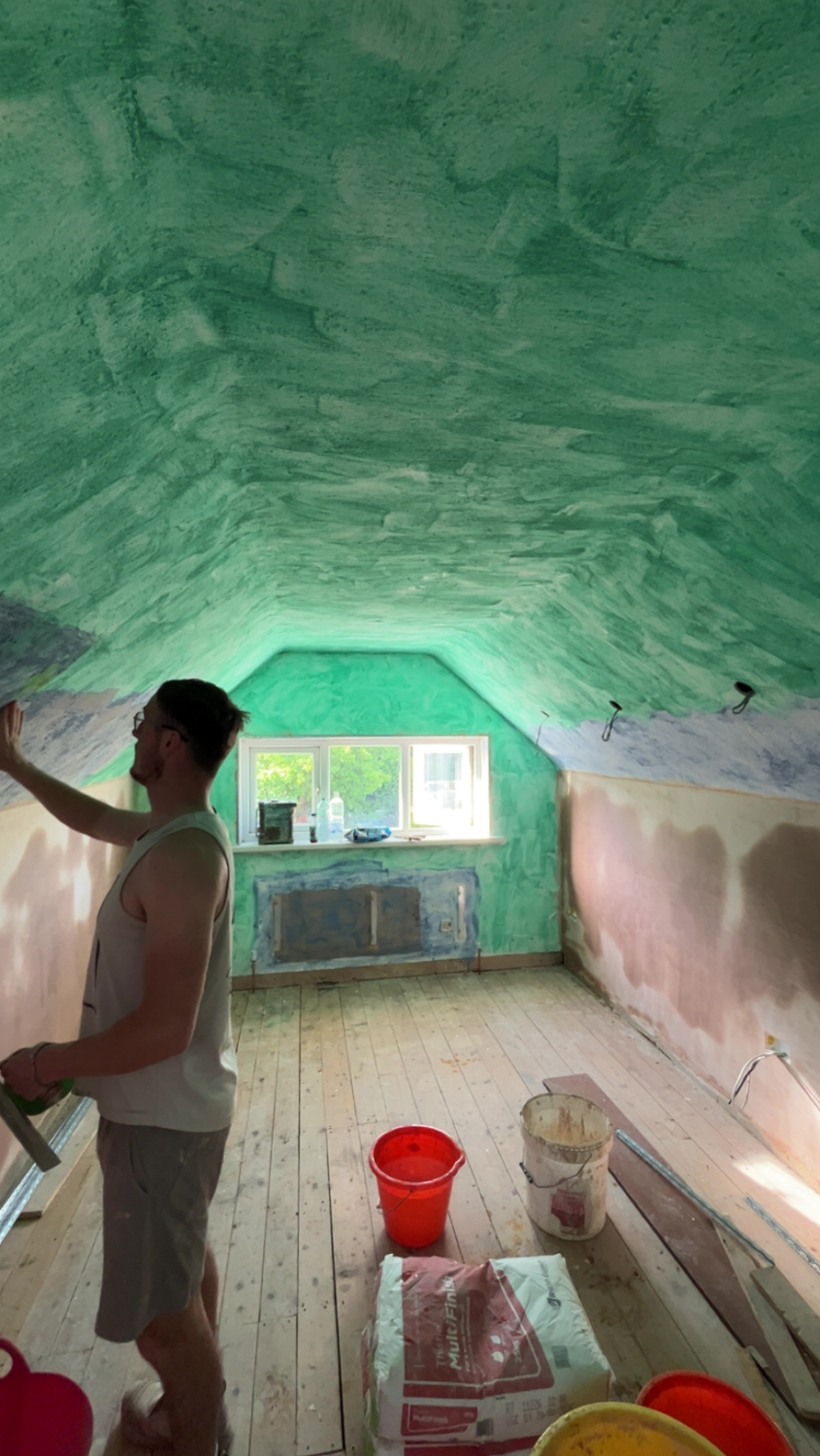 Plasterer applying a coat to a wall