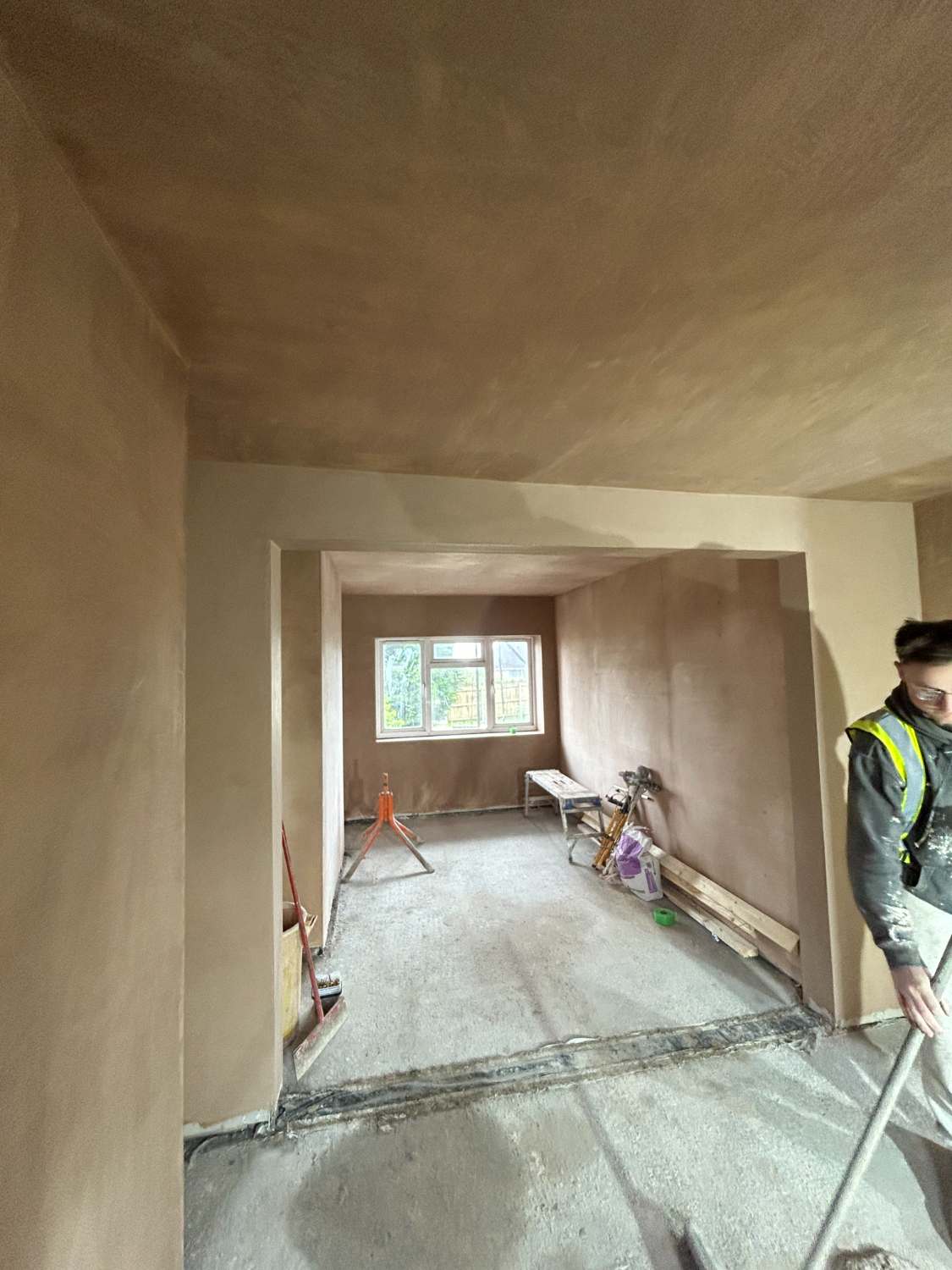 Plasterer skimming a wall beside a window